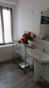 a bathroom with a sink and a shelf with flowers at HOTEL Via Emilia Ovest 224 SELF CHECK-IN in Parma