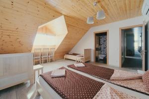 two beds in a large room with wooden ceilings at Kaimo turizmo sodyba "Ąžuola" in Vainutas