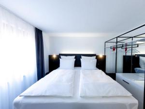 a bedroom with a large white bed with white pillows at DORMERO Hotel Aalen in Aalen