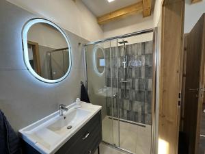 a bathroom with a sink and a shower with a mirror at Házikon 2 Apartman in Igricetanya +17 photos