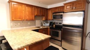 a kitchen with wooden cabinets and a stainless steel refrigerator at Broadway Beach Retreat Unit 4 in Cape May