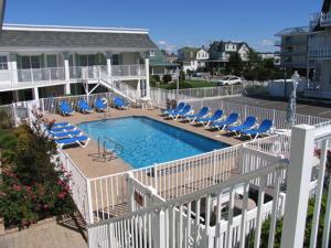a swimming pool with lounge chairs and a house at Broadway Beach Retreat Unit 4 in Cape May
