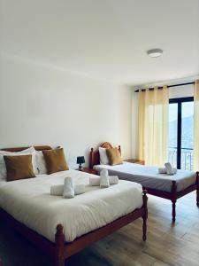 two beds sitting in a room with a window at Seaside & Levada Escape in Machico