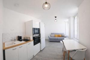 a white kitchen with a sink and a table at Bel appartement T2 centre historique in Auxerre