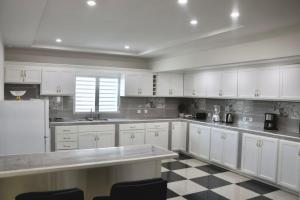 a kitchen with white cabinets and a checkered floor at Grapes of Grace in Baie Nettle