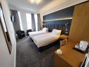a hotel room with two beds and a desk at At Caledonia in Douglas