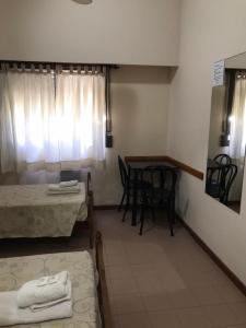 a room with two beds and a table with chairs at Hotel JR in Mar del Tuyú