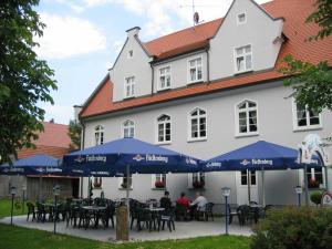 a white building with tables and blue umbrellas at Gasthof Rössle Eberhardzell in Füramoos