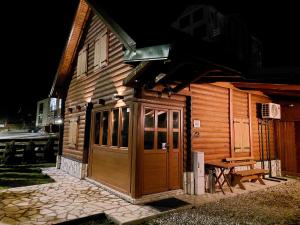 a wooden cabin with a wooden door and a bench at Zara Chalet in Kolašin