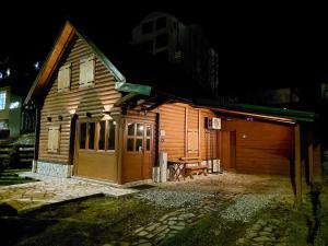 a wooden house with a garage at night at Zara Chalet in Kolašin