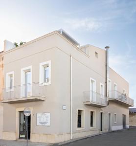 a white building with two balconies on it at Dimora Zahira Your Italian Escape in Marina di Ragusa Steps from the Sea in Marina di Ragusa