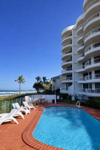 a hotel with a swimming pool and chairs and a building at Albatross North Apartments in Gold Coast