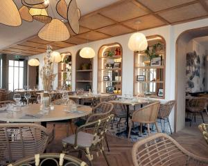 a dining room with tables and chairs and chandeliers at La Villa Rose-Marie in Saint-Brevin-les-Pins