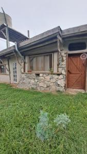 a stone house with a garage and a grass yard at Biocasa in Villa Anizacate
