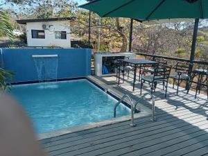 a swimming pool with a table and chairs and an umbrella at Fruta mango # 1 in Playa Guacalillo +5 photos
