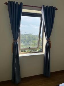 a window with blue curtains in a room at Trâm Anh Hotel in Kon Von Kla