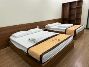 two beds in a room with wooden floors at Trâm Anh Hotel in Kon Von Kla