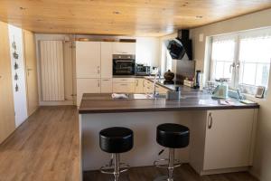a kitchen with a large island with two bar stools at Ferienhaus Hörli in Sankt Peterzell +33 photos