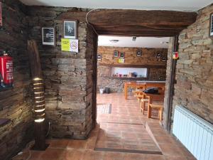 a room with a brick wall and a dining room at Albergue Val de Samos in Samos