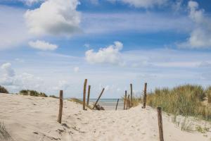 a beach with a fence in the sand and the ocean at La Clé des Sternes in Camiers
