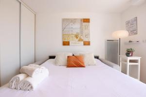 a white bedroom with a large white bed with two pillows at La Clé des Sternes in Camiers