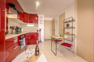 a kitchen with red cabinets and a table with a bottle of wine at La Clé des Sternes in Camiers +12 photos
