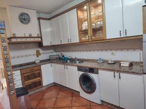 a kitchen with white cabinets and a washing machine at Casa Kamelias in Moraña