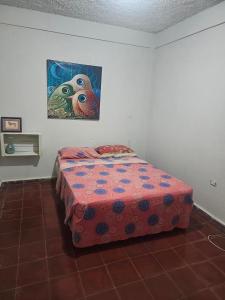 a bed in a room with a painting on the wall at Entre olas in La Libertad