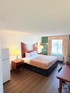a bedroom with a bed and two tables and a window at Three Rivers Motel in Fort Wayne +9 photos