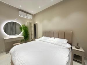 a bedroom with a large white bed and a mirror at Al Hamra Modern Suite, Khobar in Al Khobar