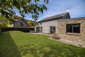 a house with a grass yard in front of it at Chartres Retreat in Arrowtown