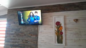 a flat screen tv hanging on a brick wall at Manhuemalal in Villarrica