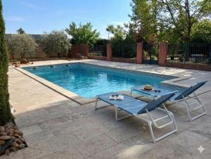 a swimming pool with two chairs and a table at Studio Chez Joelle in Carpentras