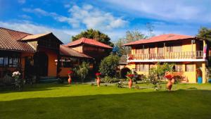 a yard with chickens in the grass next to a building at Las Orquídeas Runtun Lodge in Baños