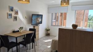 a living room with a table and a tv on the wall at Solar Andino Inn in San Carlos de Bariloche
