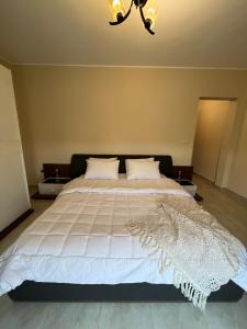 a bedroom with a large white bed with a chandelier at Quiet Comfy Stay in Burg el-Ḥudûd