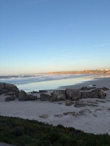 a beach with rocks in the sand and water at Casa São Marcos II in Peniche