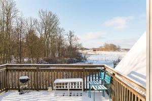 a deck covered in snow with two chairs and a grill at Comfortable room with beautiful nature in Malmo in Malmö