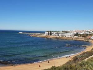 a beach with people on the sand and the ocean at Casa da Baleia Ericeira in Ericeira