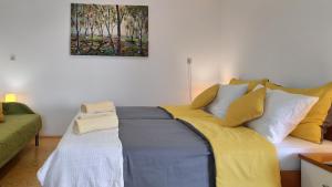 a bed with yellow and white pillows in a room at Peaceful Family Apartments near Terme Čatež in Čatež ob Savi +28 photos