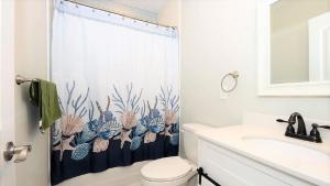 a bathroom with a shower curtain with a toilet and a sink at Bay Breeze in Town Bank +20 photos