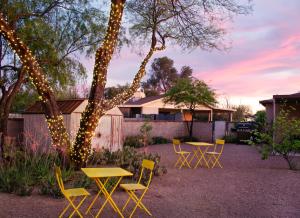 a patio with yellow tables and chairs and a tree with lights at Sonoran Peach - Light-Filled 5BR near TMC in Tucson