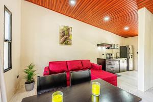 a living room with a red couch and a kitchen at Mountain Whisper in Tilarán