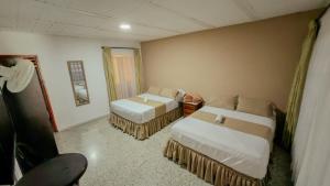 a hotel room with two beds and a chair at HOTEL DULCES SUEÑOS N°2 in Tuluá