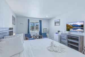a bedroom with a large white bed and a tv at RiverWalk Inn in Pagosa Springs