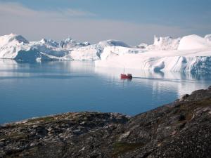 a boat in a body of water next to an iceberg at Hotel Arctic in Ilulissat