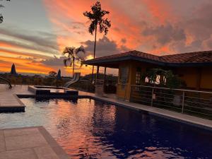 a swimming pool in front of a house with a sunset at Ecohotel Guaduales Nature in Pereira