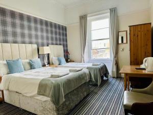 a bedroom with two beds and a desk and a window at Edinburgh full bliss in Edinburgh