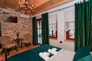a bedroom with green curtains and a bed and a table at Alchemist Inn in Gjirokastër