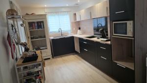 a kitchen with black cabinets and a sink at Chambre privée villa montelimar in Montélimar
